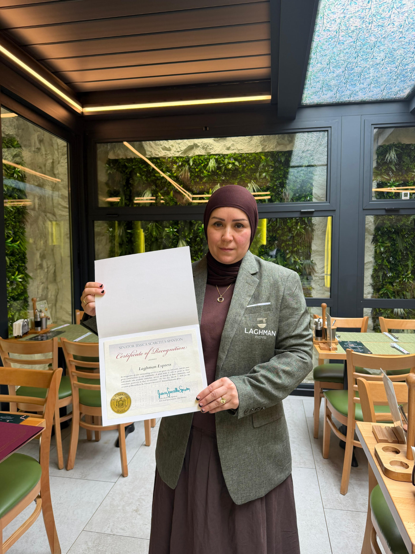 Gulnoza Jurayeva holding a Certificate of Recognition from the New York State Senate awarded to Laghman Express