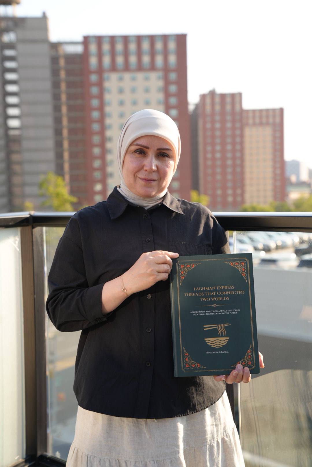 Gulnoza Jurayeva holding the book Laghman Express: Threads That Connected Two Worlds